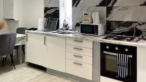A modern kitchen with a built-in microwave, coffee maker, and stove. - Apartment - Sleeps 4 - Parking - WiFi (Greater London, Dagenham)
