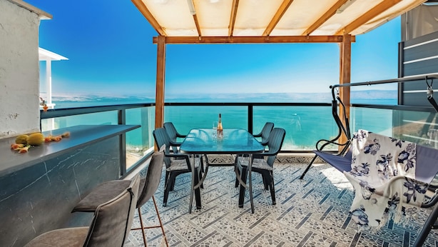 A terrace with a glass table and chairs, overlooking a body of water. - Sea of Galilee Panorama Apt by SeaN'Rent (Tiberias)