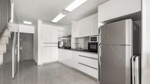 A modern kitchen with white cabinets, stainless steel appliances, and a tiled floor. - Sea of Galilee Panorama Apt by SeaN'Rent (Tiberias)