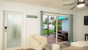 A room with a sliding glass door leading to a patio, a ceiling fan, and a sign that reads 'SIESTA KEY.' - Siesta Key Village • Pool • Walk to Beach • Pets (Sarasota)