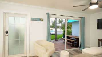 Una habitación con puerta de vidrio corredera que da a un patio, ventilador de techo y un letrero que dice 'SIESTA KEY'.