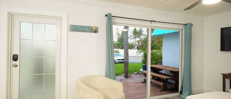 A room with a sliding glass door leading to a patio, a ceiling fan, and a sign that reads 'SIESTA KEY.'