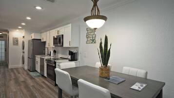 A modern kitchen with white cabinets, stainless steel appliances, and a dining area with a table and chairs.