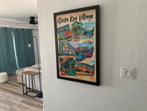 A framed poster of Siesta Key Village on a white textured wall.