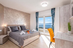 Ein modernes Schlafzimmer mit einem großen Bett, einem Schreibtisch und Blick aufs Meer.