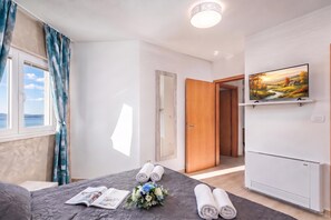 Une chambre d’hôtel avec un lit, une télévision, une fenêtre avec des rideaux et une porte donnant sur une autre pièce.