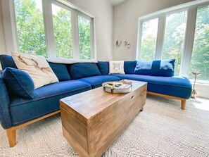 A living room with a blue sofa, a wooden coffee table, and patterned carpet.