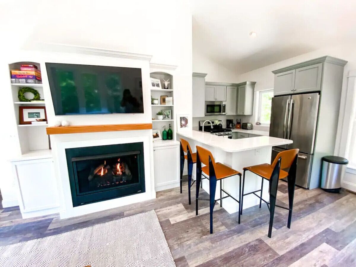 A modern kitchen with a central island, a fireplace, and bar stools.