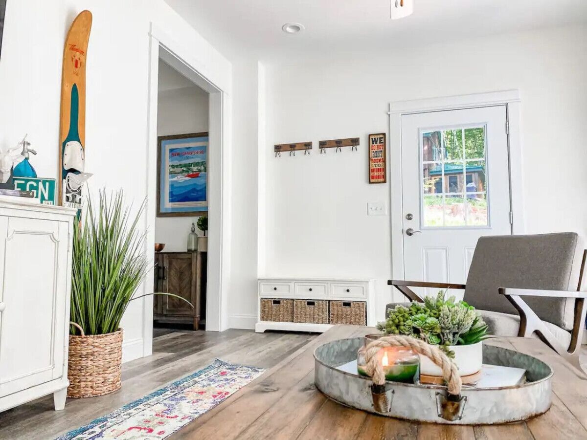 A living room with a white cabinet, a plant, a round coffee table with a candle, and a door with a window view.