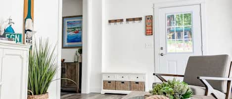 A living room with a white cabinet, a plant, a round coffee table with a candle, and a door with a window view.