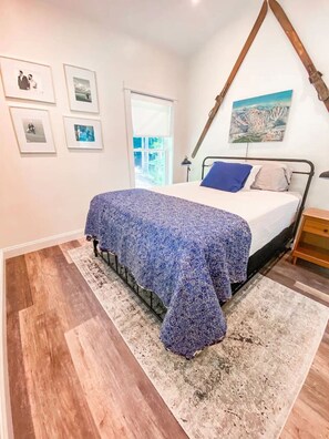 Une chambre à coucher avec un lit, une fenêtre et un tableau accroché au mur.