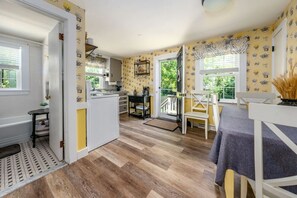 Cocina con comedor, puerta que da al exterior y vista a follaje.