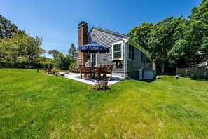A house with a patio, a chimney, and a well-maintained lawn.