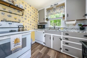 A kitchen with a stove, microwave, and dishwasher. There is a window with a view of greenery outside.