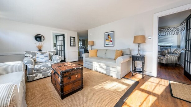 A spacious living room with a sofa, a patterned armchair, a wooden chest, and a lamp. - New! Chatham Cottage- 1 Mile to Downtown & Beaches (Chatham)