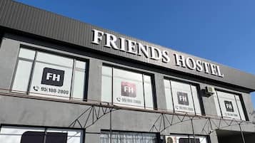 A building with a sign reading 'FRIENDS HOSTEL' and multiple windows with 'FH' logos and contact numbers.