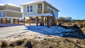 A beachfront house with a wooden deck and a staircase leading to the main entrance. - Modern Little Beach House- Steps to the Beach (Gulf Shores)