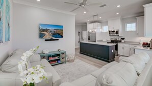 A modern kitchen with white cabinets, a central island, and stainless steel appliances. - Modern Little Beach House- Steps to the Beach (Gulf Shores)
