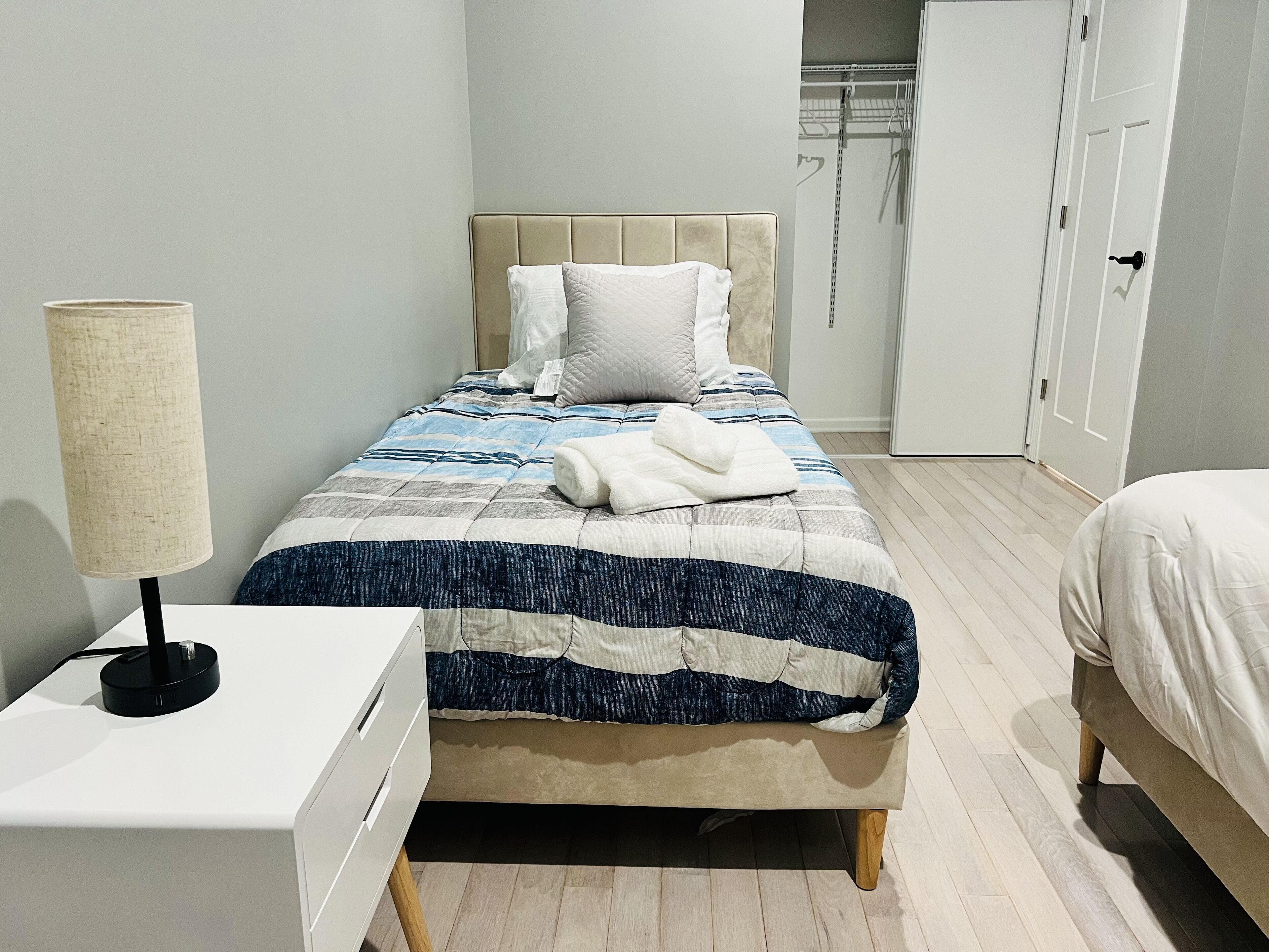 A bedroom with a bed, bedside table, lamp, and wardrobe.