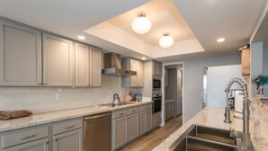 Una cocina moderna con armarios grises claros, electrodomésticos de acero inoxidable y encimera de granito.