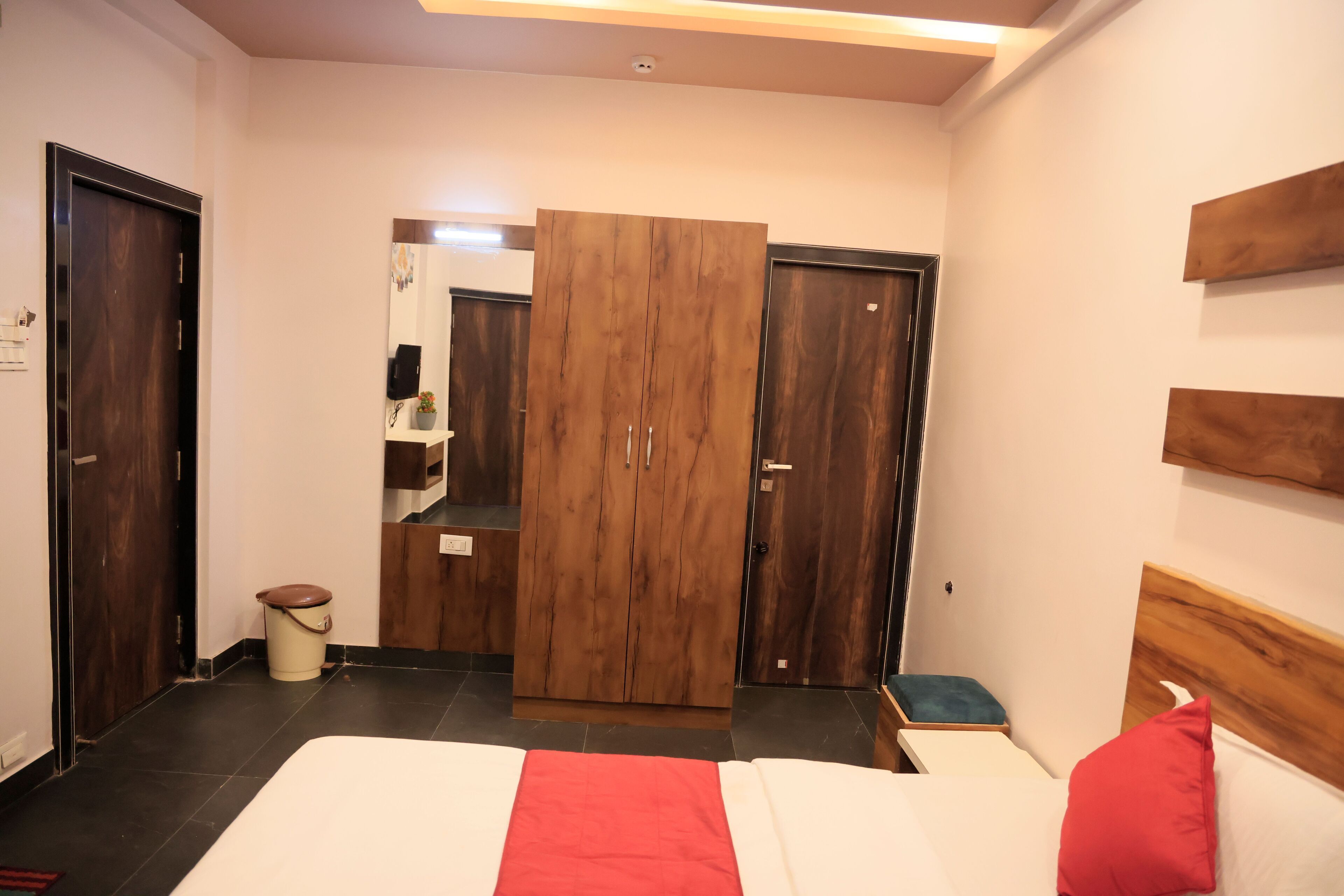 Una habitación de hotel con cama, armario, mesita pequeña y mesita de noche.