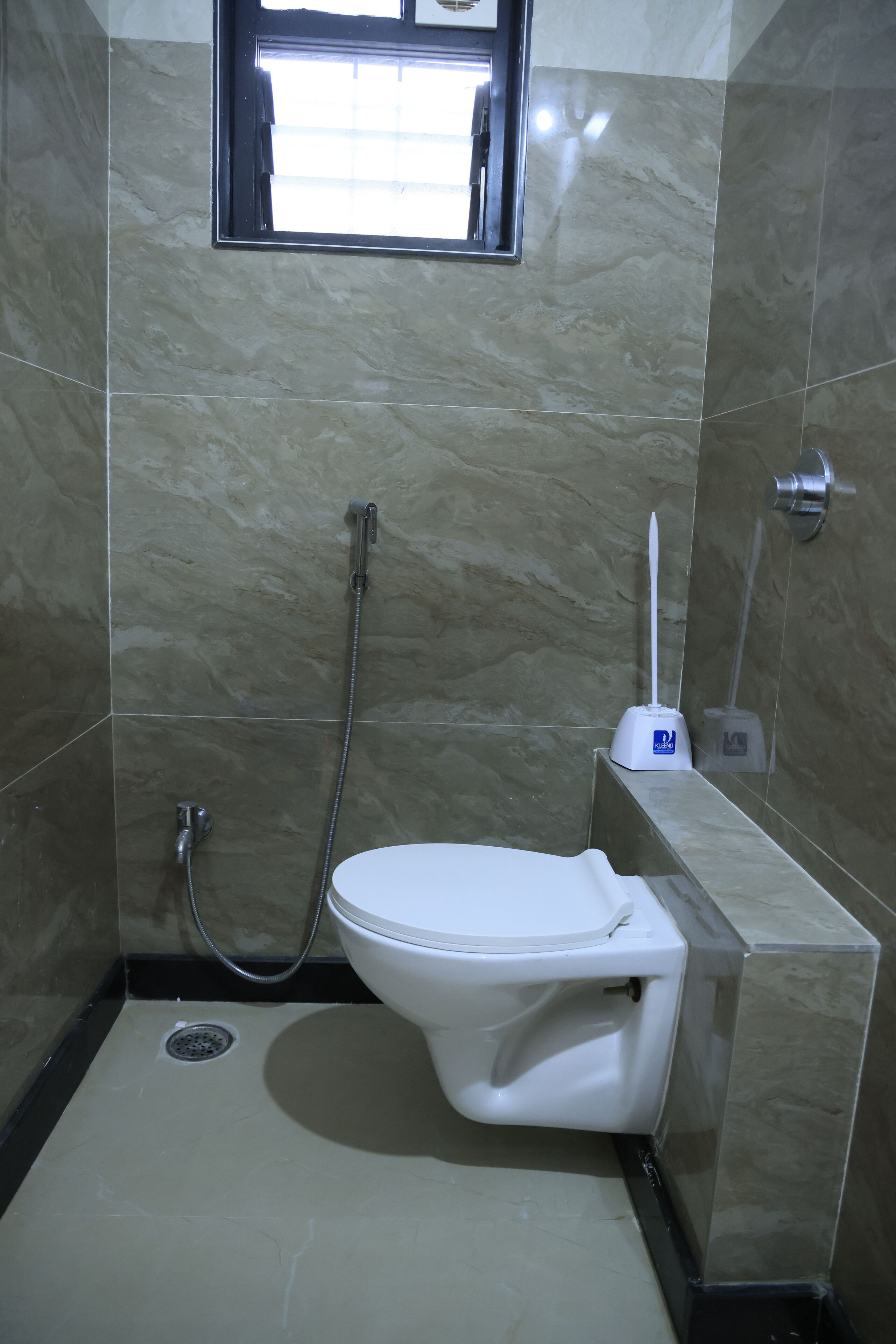 Ein Badezimmer mit Toilette, Duschbrause und einem Fenster.