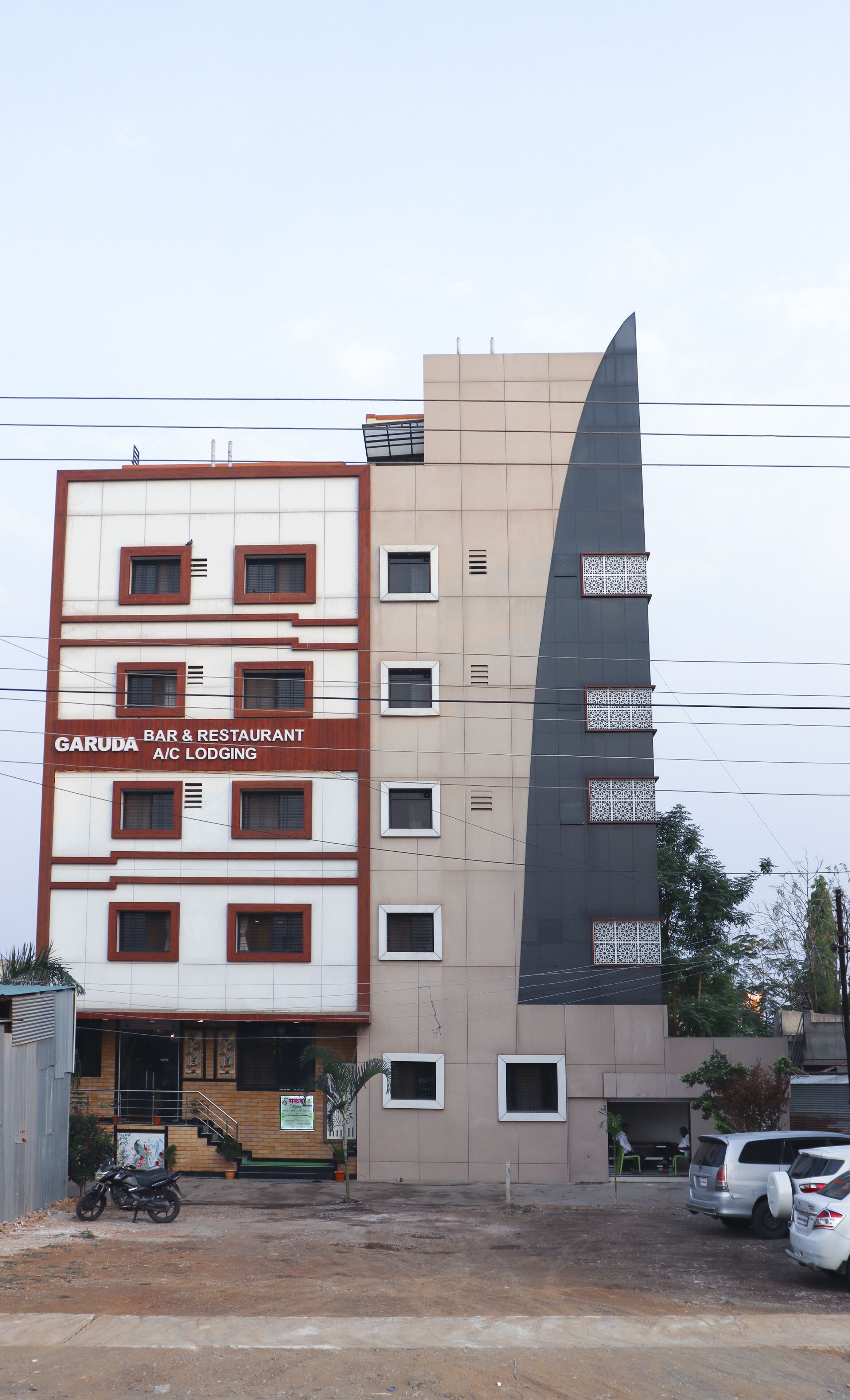 A multi-story building with a sign for 'GARUDA BAR & RESTAURANT A/C LODGING'.