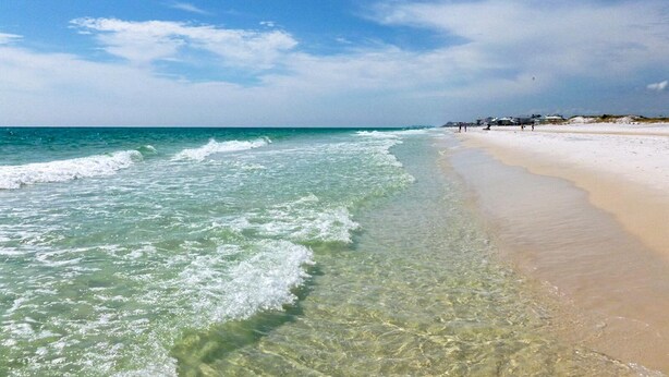 Una playa con agua cristalina y una orilla arenosa.