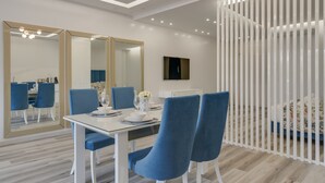 Un espace repas moderne avec une table blanche, des chaises bleues et un grand miroir.