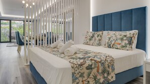 Une chambre moderne avec un grand lit, une vue sur l’extérieur et un coin salon comprenant une chaise et une table.