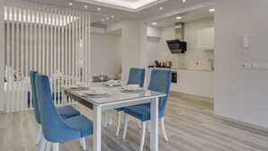 Un espace repas moderne avec une table en verre, des chaises bleues et des murs blancs.
