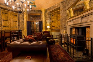 Ein gemütliches Wohnzimmer mit Ledersofa, Kamin und einer Chandelier.