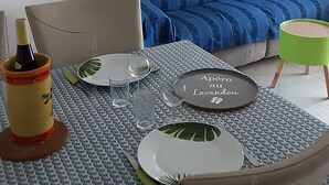 A dining area with a table set for two, a sofa, and a small green stool.