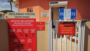 A red sign with French text indicating rules for a mandatory shower area, a door labeled "Douche Shower", and a sign for a mandatory bracelet port.