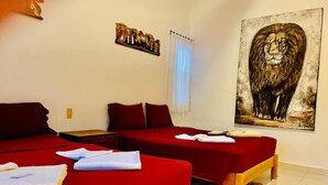 Ein Hotelzimmer mit zwei Einzelbetten, einem hölzernen Nachttisch, einem roten Sofa und einem großen Gemälde eines Löwen.