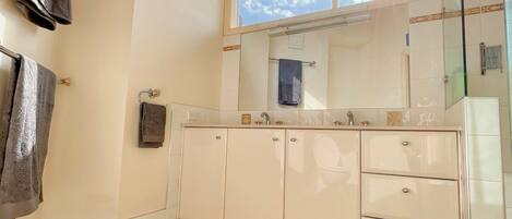 A bathroom with a large window, a mirror, a sink, and a towel rack.