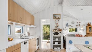 Une cuisine moderne avec des meubles en bois, un four encastré et un coin repas comprenant une table et des chaises.