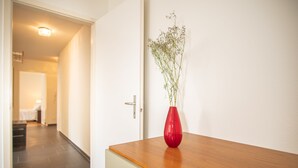 A hallway with a wooden table and a red vase with flowers.