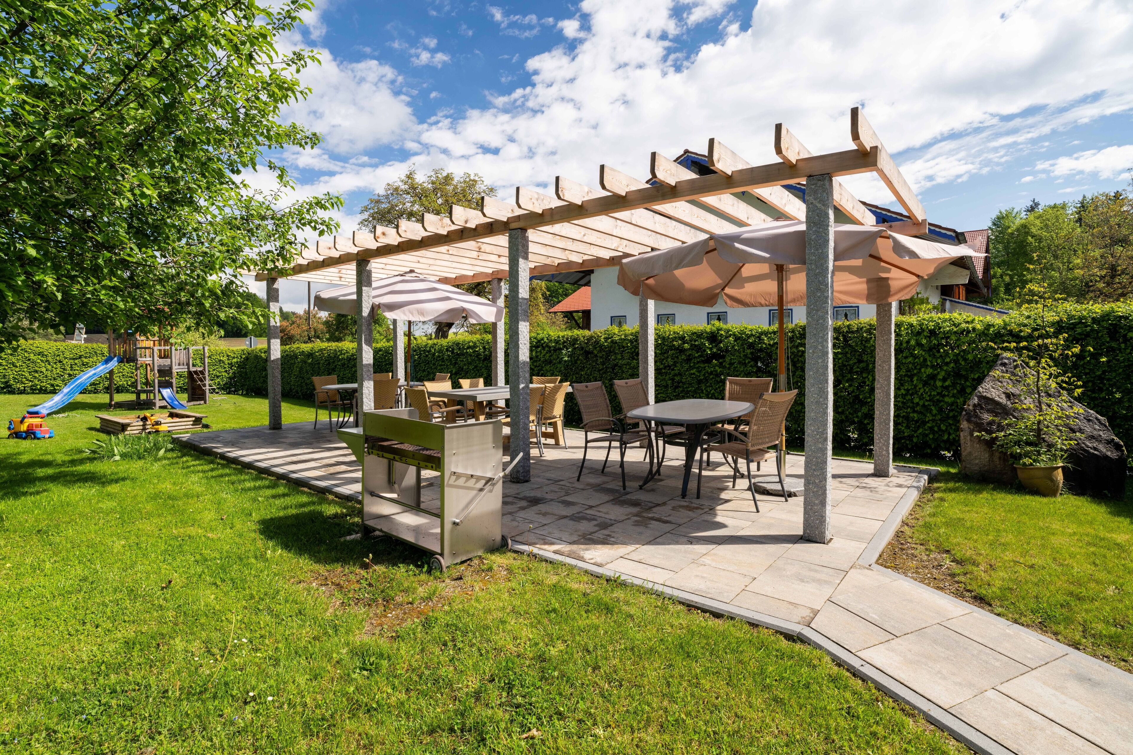 A covered patio area with outdoor furniture, a slide, and a stone pathway.