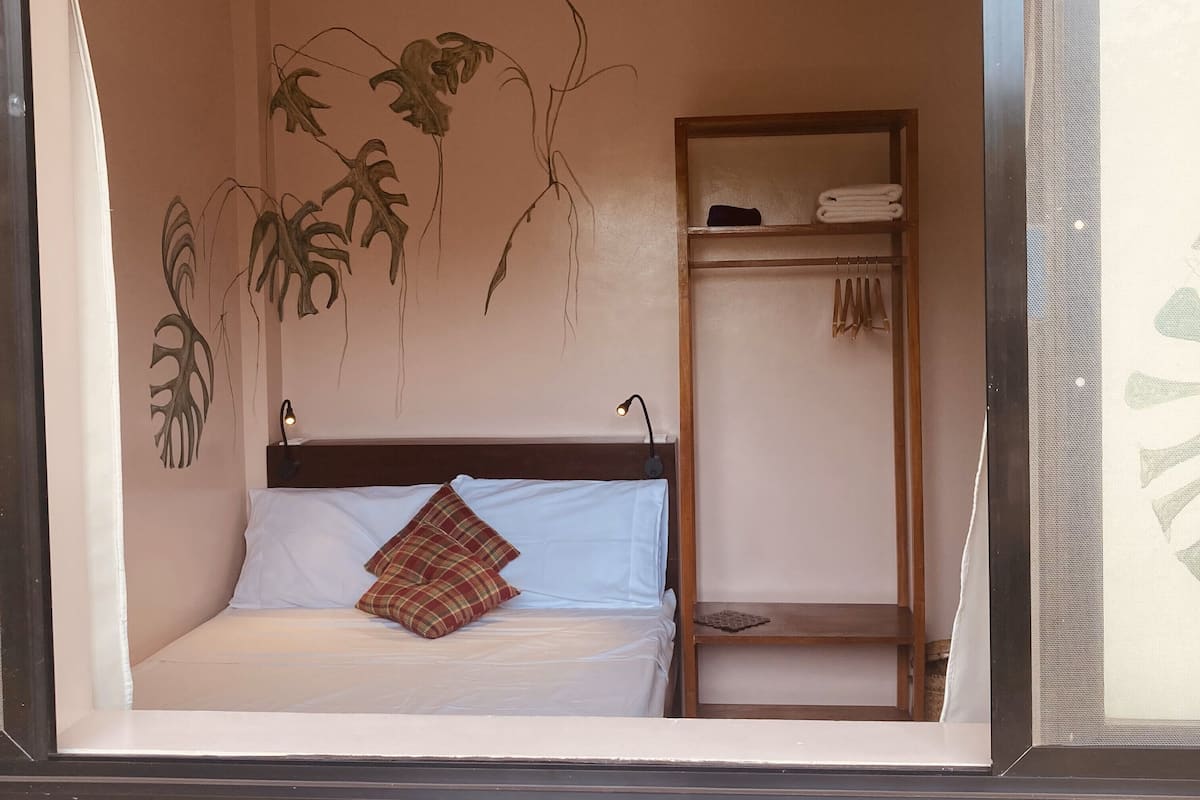 Une chambre à coucher comprenant un lit, une table de chevet, une étagère avec des serviettes et des œuvres d’art murales.