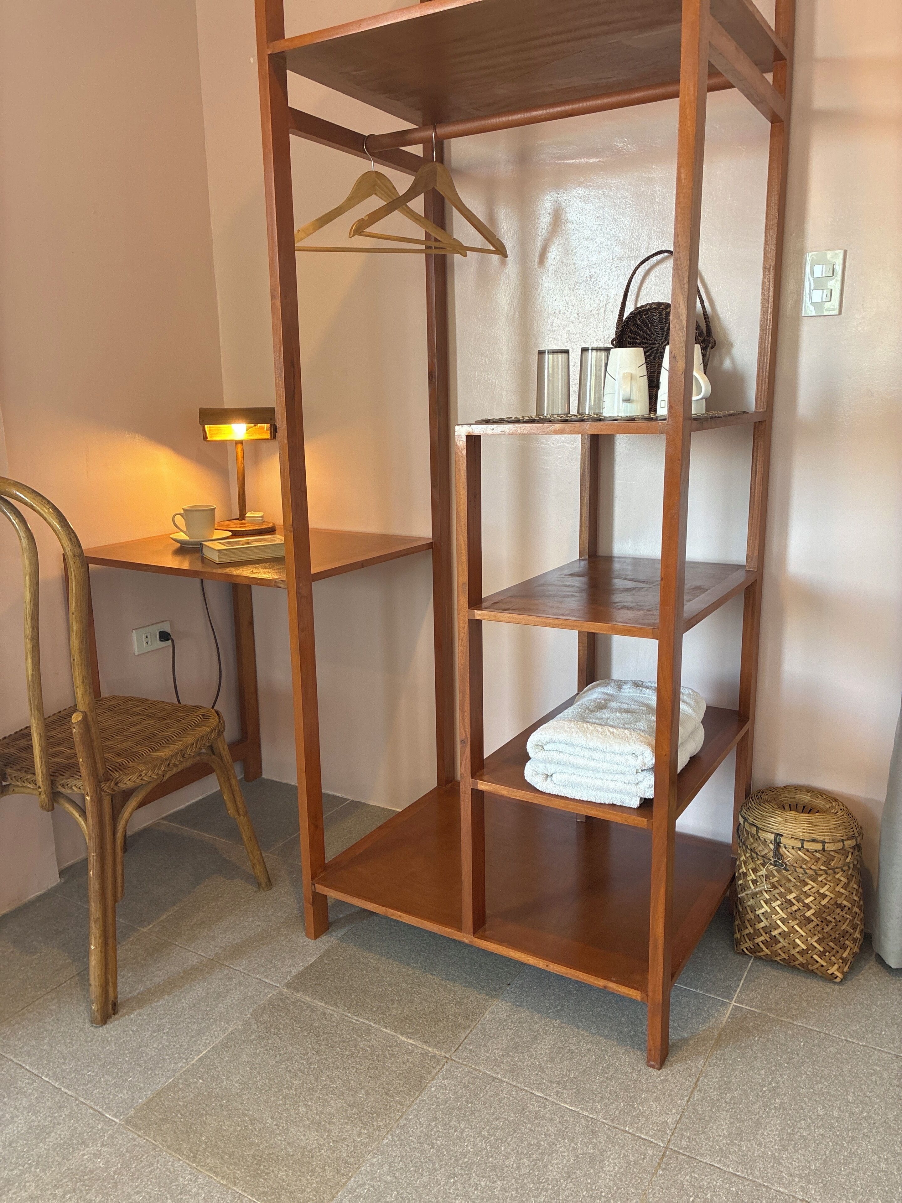 A wooden shelf unit with a chair, a lamp, and towels.
