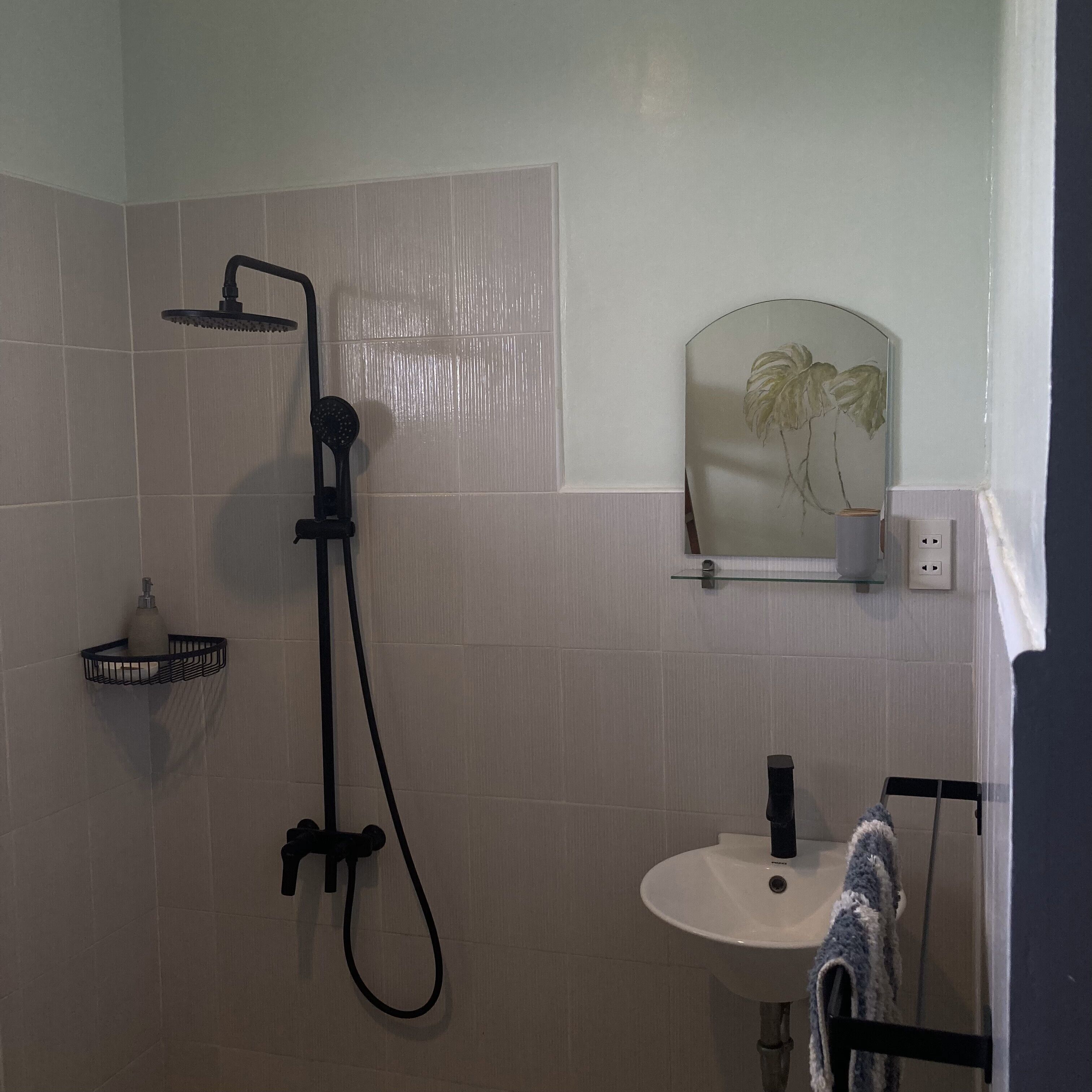 Ein Badezimmer mit Dusche, Waschbecken und einem Spiegel mit dekorativem Rahmen.