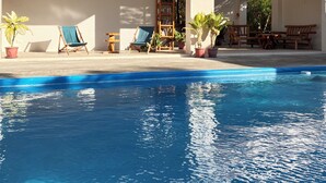 A swimming pool with lounge chairs and potted plants. - The Lazy Tiki (Buenavista)