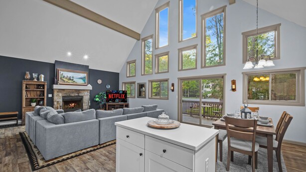 A spacious living room with a sectional sofa, a fireplace, and a dining area with a table and chairs. - Hot Tub Chalet, Fire Pit, Lake Access, Dogs OK (Blakeslee)