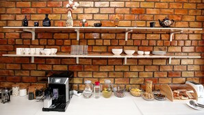 Eine Küche mit Backsteinwand, Regalen mit Küchenutensilien und einer Kaffeemaschine.