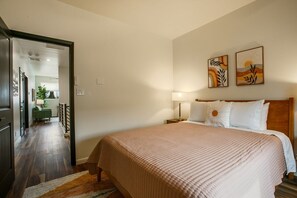 Een hotelkamer met een groot bed, een nachtkastje, een lamp en twee decoratieve wandpanelen.