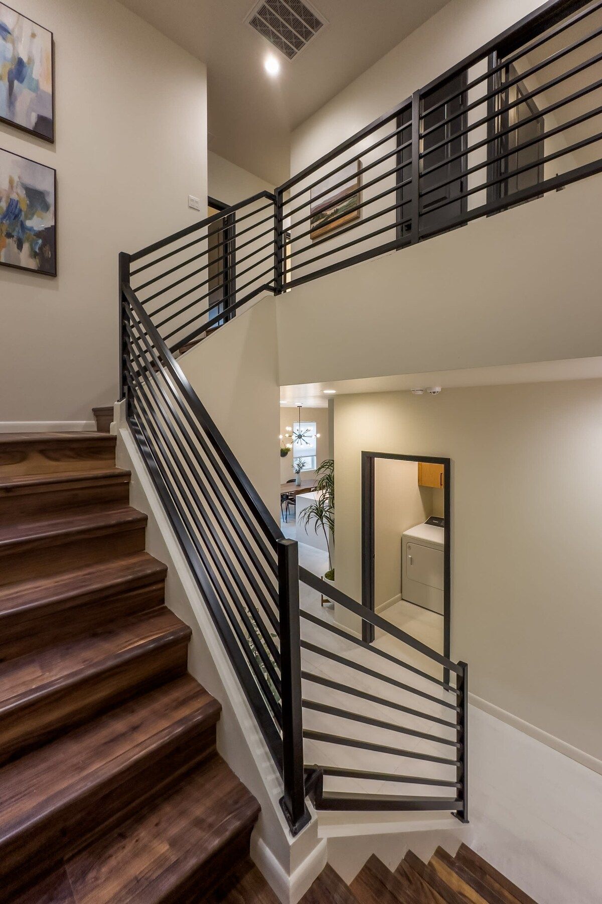 A staircase with wooden steps and black metal railings leading to an upper level.