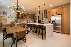 Een moderne keuken met een centraal eiland, houten kastjes en een roestvrijstalen koelkast.