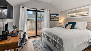 A bedroom with a bed, a desk with a computer, a ceiling fan, and a window with curtains.
