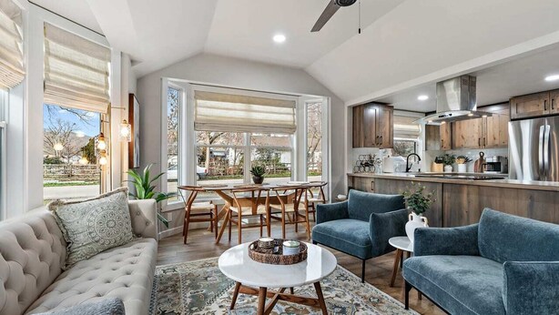 A modern kitchen with stainless steel appliances, wooden cabinets, and a dining area with a round table and chairs.